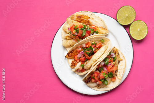 Photography Mexican fish tacos also called Baja with fresh sauce on pink background