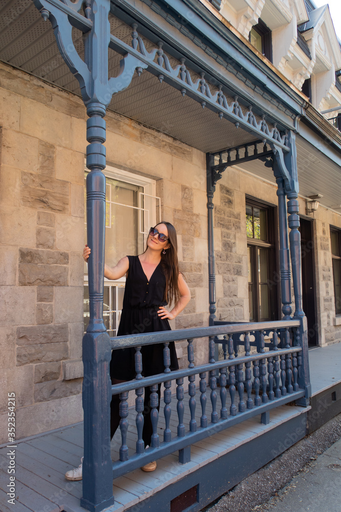 Young woman standing on the front porch of a typical house in Montreal, Canada Young woman standing on the front porch of a typical house in Montreal, Canada