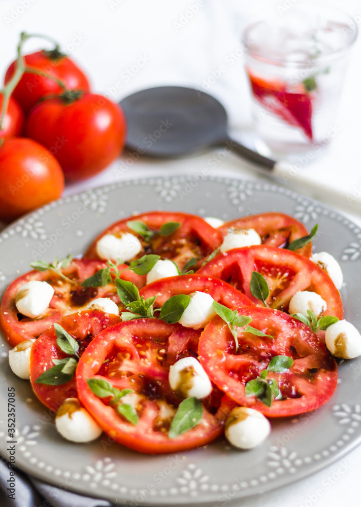 Homemade Caprese Salad on a white surface and gray dish with a rustic napkin Homemade Caprese Salad on a white surface and gray dish with a rustic napkin