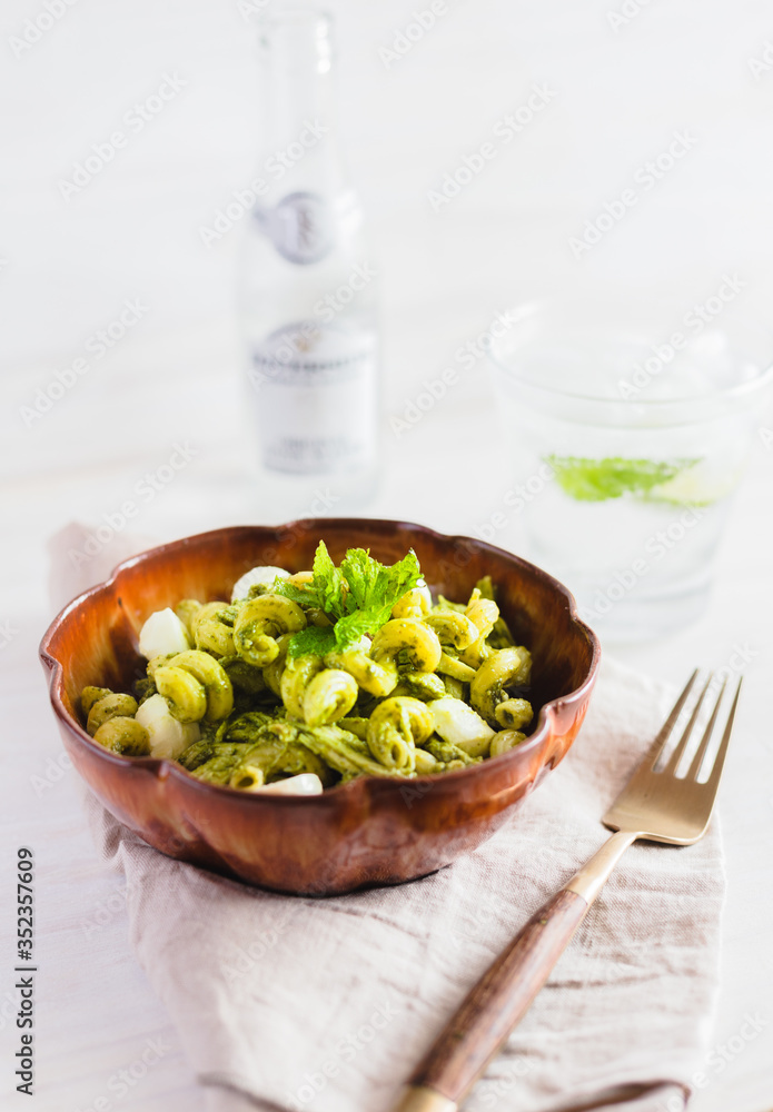 Obraz premium Homemade pasta salad with pesto and buffalo mozzarella on a white surface and rustic napkin