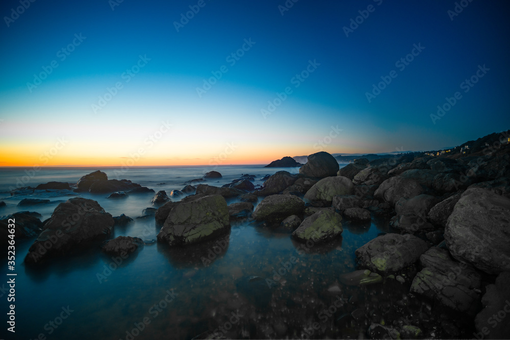 Stones in the water of the Pacific Ocean, with rocks in the water at sunset. Night landscape