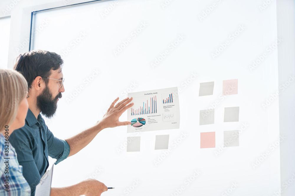 employees discussing financial data standing near the Board employees discussing financial data standing near the Board