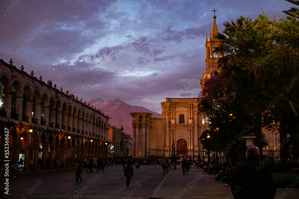 Obraz premium The view of Plaza de Armas, historical center of Arequipa with the Cathedral and stunning purple clouds and sunset mountains in the back 