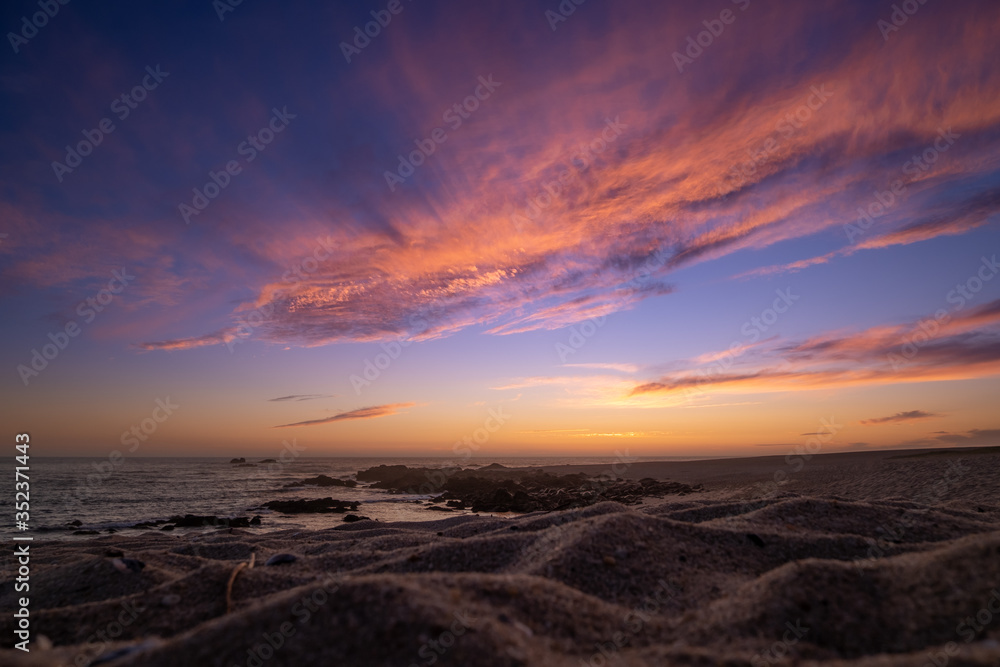 Sunset on beach. Low angle shot over sandy beach to ocean with dramatic, colorful sky. Sunset on beach. Low angle shot over sandy beach to ocean with dramatic, colorful sky.