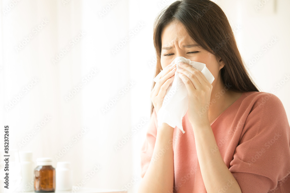 sick asian young woman sneezing into tissue paper while and sitting on bed in the bedroom sick asian young woman sneezing into tissue paper while and sitting on bed in the bedroom