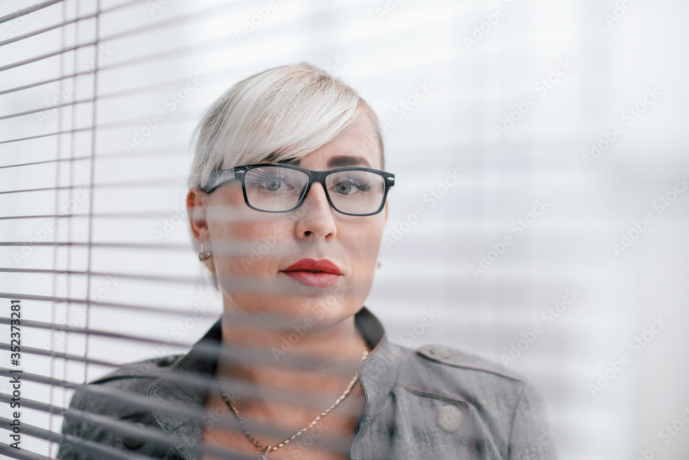 close up. business woman looks somewhere through the office window.