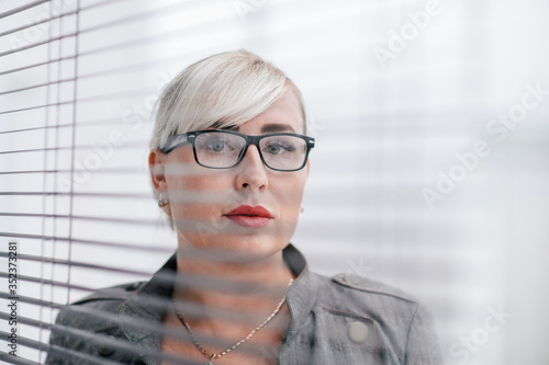 close up. business woman looks somewhere through the office window.