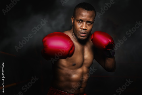 african american boxer punching with glove in dark background © Mongkolchon