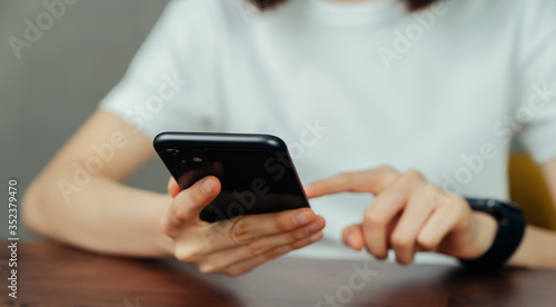 Closeup of young woman hand holding smartphone and chatting with friends at social network.