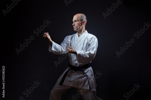 On a black background a young athlete stands in a karate stand