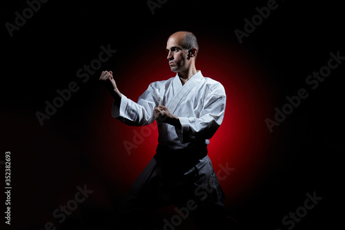 On a red gradient background a young athlete stands in a karate stance