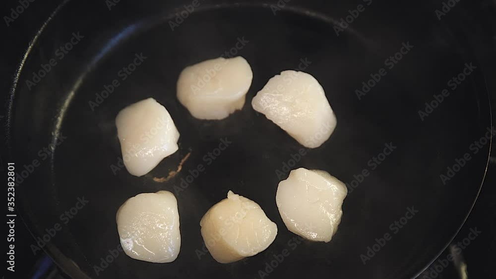 the chef is cooking scallops. Scallop is cooking in a pan. Someone's cooking seafood. Close-up of the scallop. the chef is cooking scallops. Scallop is cooking in a pan. Someone's cooking seafood. Close-up of the scallop.