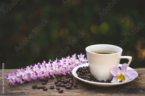 Cup coffee, wild fragrance orchid and roasted coffee bean on wooden table.