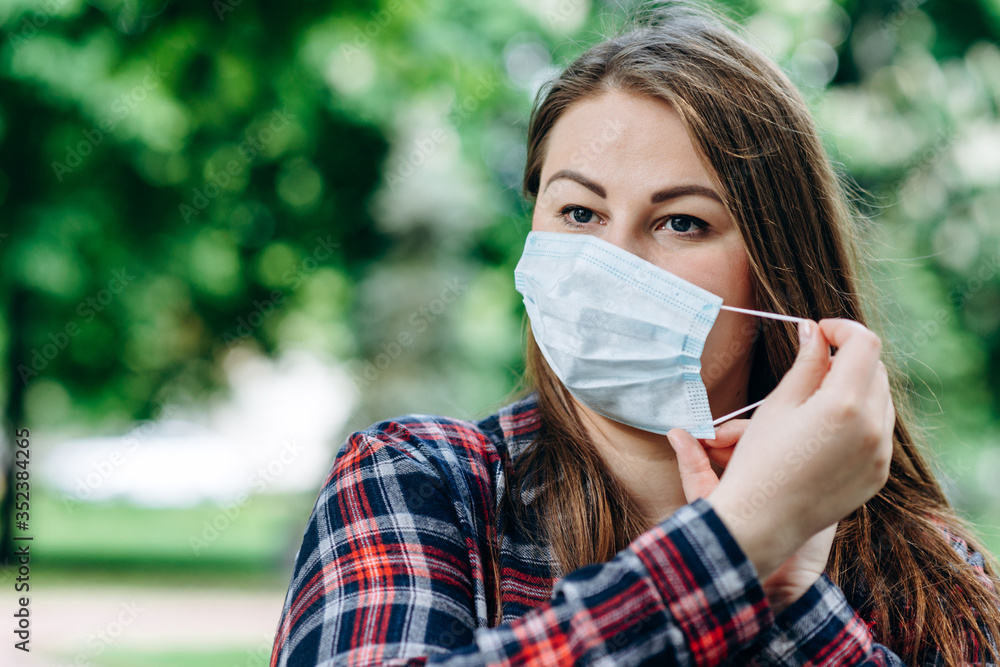 Beautiful woman takes off protective mask outdoors Beautiful woman takes off protective mask outdoors