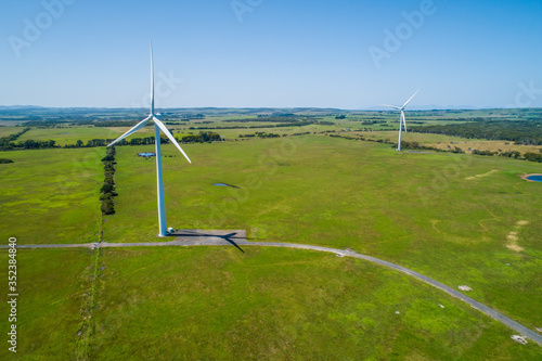 Two wind turbines among green grazelands in the countryside - aerial landscape photo