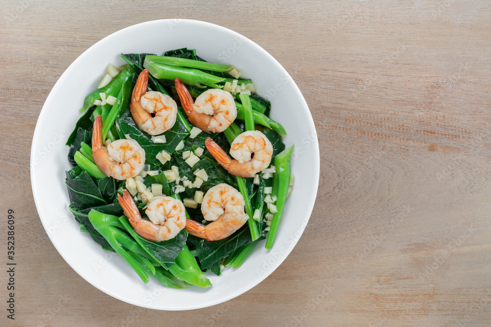 top view of stir fried chinese kale with shrimps in a ceramic bowl on wooden table. asian homemade style food concept. top view of stir fried chinese kale with shrimps in a ceramic bowl on wooden table. asian homemade style food concept.