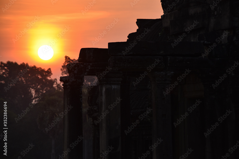 Morning landscape with beautiful sunrise over the forest and ancient ruins illuminated by the first rays of the sun in Cambodia