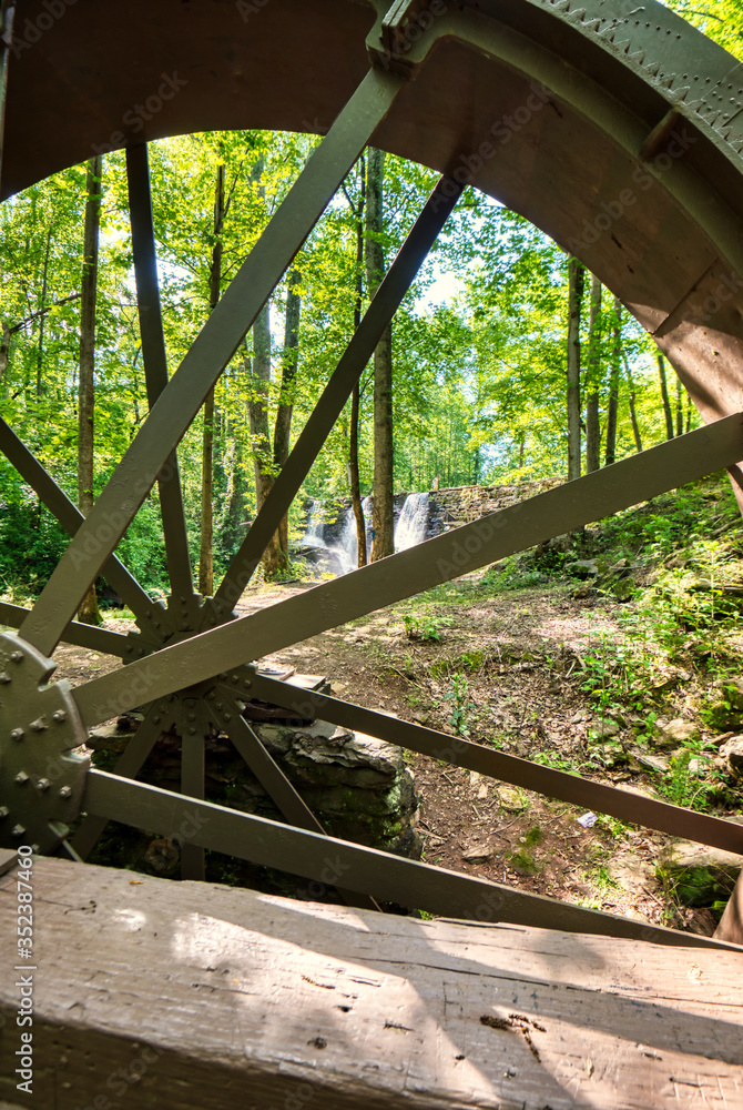 A view of a dam and waterfall looking through an old water wheel. A view of a dam and waterfall looking through an old water wheel.
