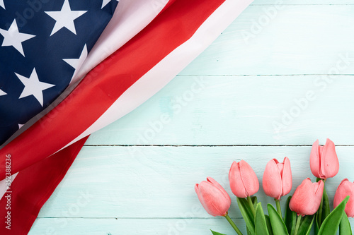Fototapeta Naklejka Na Ścianę i Meble -  US American flag with tulip flower on blue wooden background. For USA Memorial day,  Presidents day, Veterans day, Labor day, Independence or 4th of July celebration. Top view, copy space for text.