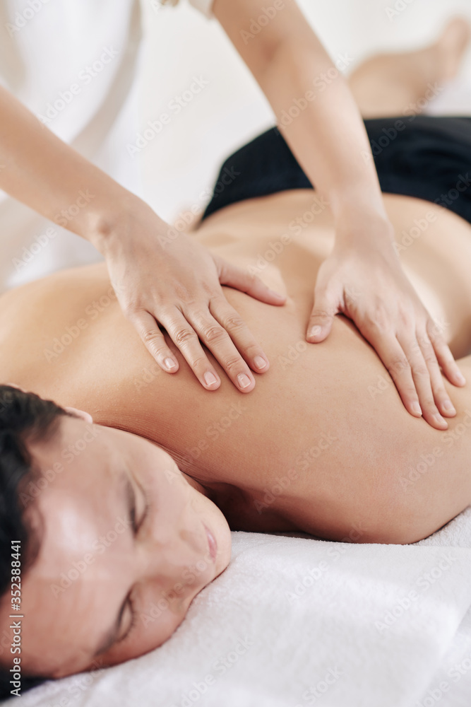Asian young man receving back massage on spa salon, relaxing and enjoying soft strokes Asian young man receving back massage on spa salon, relaxing and enjoying soft strokes
