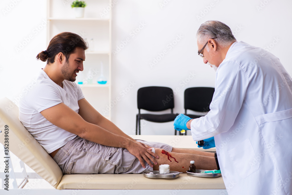 Fototapeta premium Leg injured man visiting old doctor in first aid concept