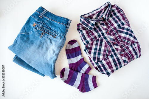 Clothing, folded plaid shirt and jeans, striped socks on a light background