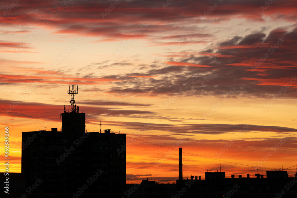 Buildings on a sunset background. Beautiful red sunset with gloomy clouds. The day is ending.