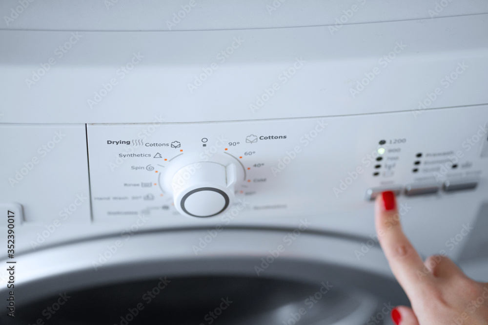 The girl sets the washing program for the washing machine. The girl sets the washing program for the washing machine.