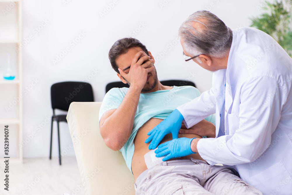 Obraz premium Injured young man visiting experienced male doctor