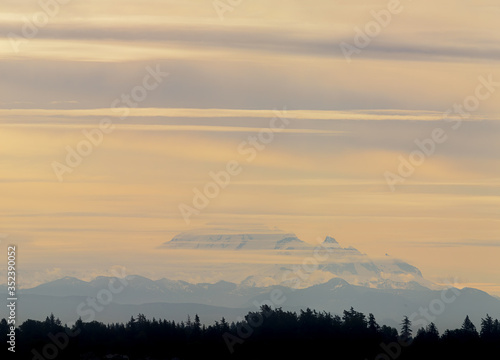 Mt Baker Washington wakes up to an orange glow and strips of cloud.