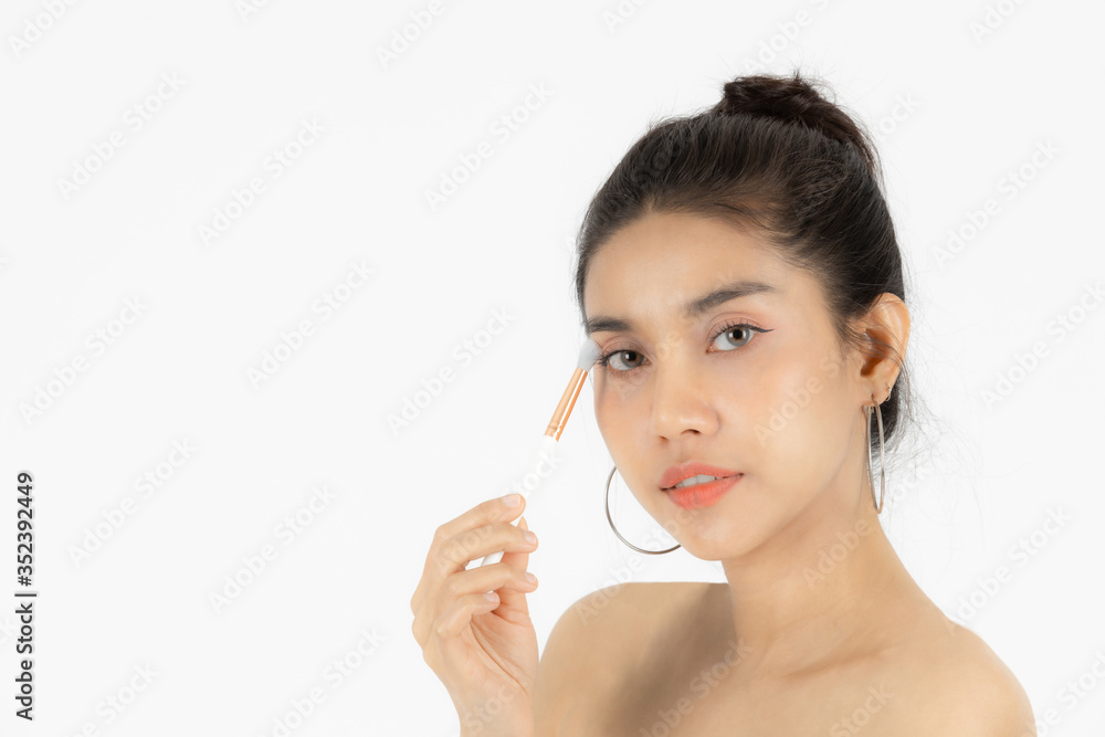 Beauty face of young Asian woman applying make up with brush over white isolated background. Healthy and cosmetics concept. Beauty face of young Asian woman applying make up with brush over white isolated background. Healthy and cosmetics concept.