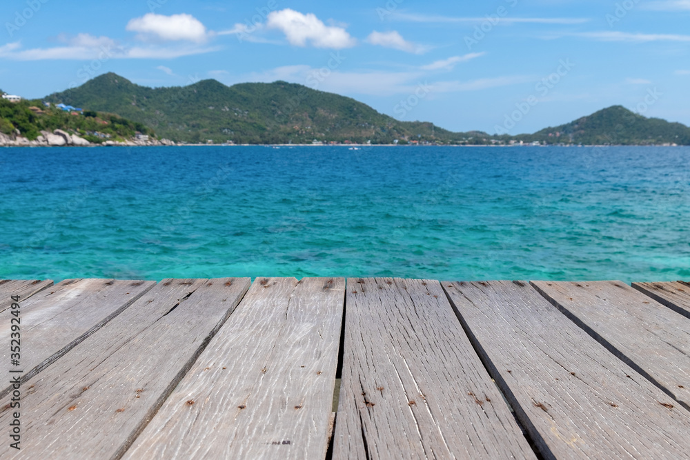 Old wooden platform beside the sea under the blue sky. Wood deck with blue ocean background. Old wooden platform beside the sea under the blue sky. Wood deck with blue ocean background.