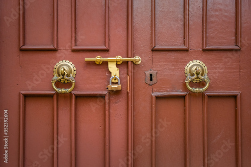 Red wooden door with gold antique handle. Details Classic vintage doors of the interior element.