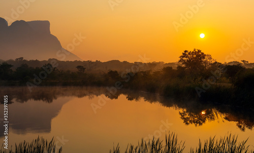 Panorama of Hanging Lip or Hanglip mountain at sunrise in the mist by a swamp lake, Entabeni Safari Game Reserve, Limpopo Province, South Africa. photo