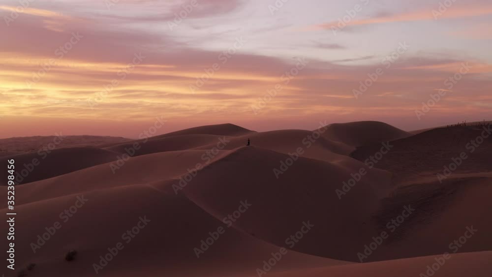 A lone figure atop a sand dune can be seen in the distance. A lone figure atop a sand dune can be seen in the distance.