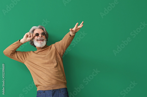Cool senior man dancing against color background © Pixel-Shot