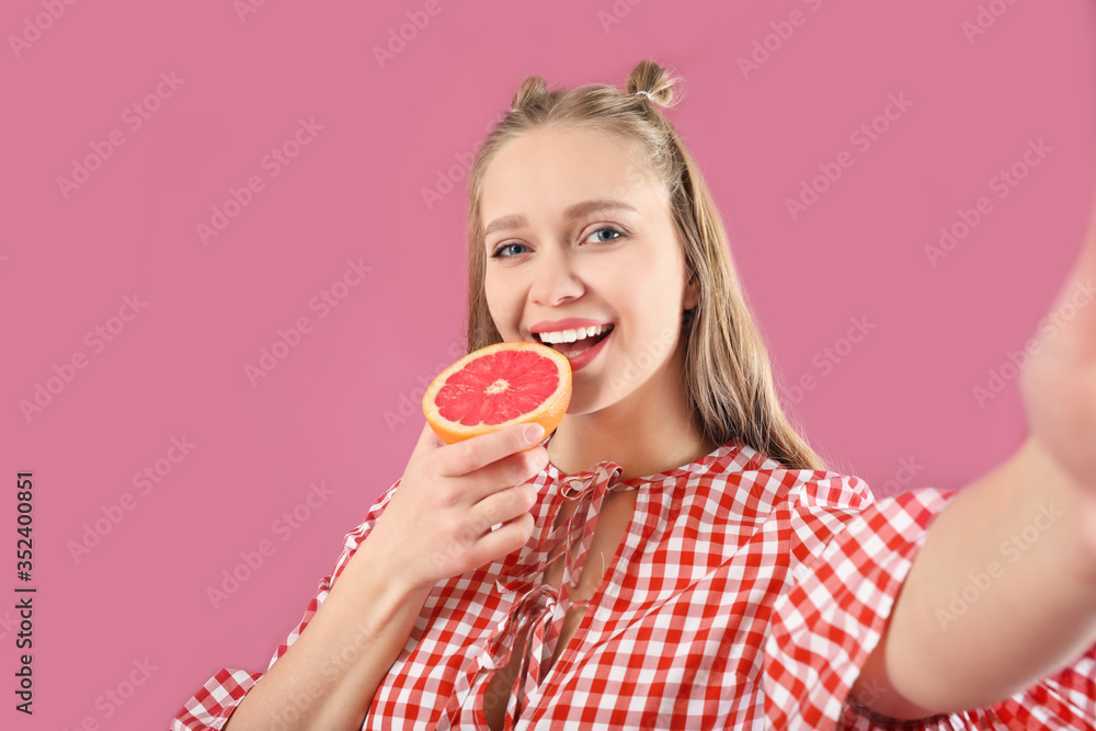 Young woman with grapefruit taking selfie on color background. Diet concept Young woman with grapefruit taking selfie on color background. Diet concept