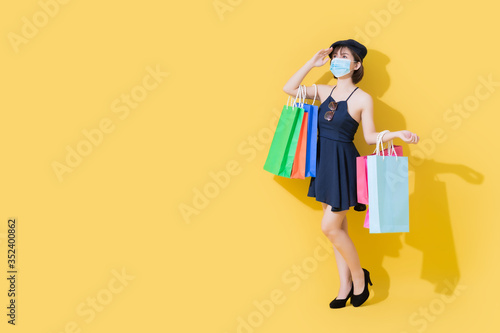 When the coronavirus crisis or covid19 improves. Cute Asian women wear blue dresses. She wears surgical masks and carrying shopping bags. She uses her hands to block the light.