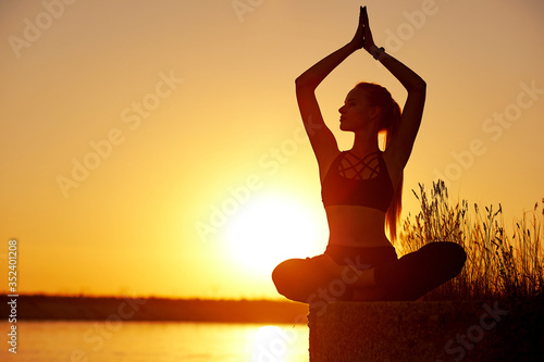 Fototapeta Naklejka Na Ścianę i Meble -  Silhouette woman with yoga posture on the beach pier at sunset or sunrise