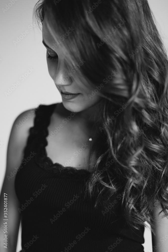 A close-up portrait of a brown-eyed brunette woman of 32 years with beautiful healthy hair in a black top on a white background. Soft selective focus. Black and white art photo. A close-up portrait of a brown-eyed brunette woman of 32 years with beautiful healthy hair in a black top on a white background. Soft selective focus. Black and white art photo.