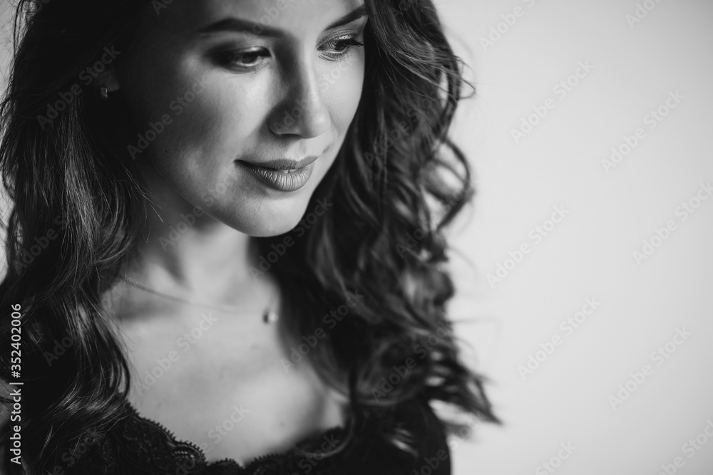 A close-up portrait of a brown-eyed brunette woman of 32 years with beautiful healthy hair in a black top on a white background. Soft selective focus. Black and white art photo. A close-up portrait of a brown-eyed brunette woman of 32 years with beautiful healthy hair in a black top on a white background. Soft selective focus. Black and white art photo.
