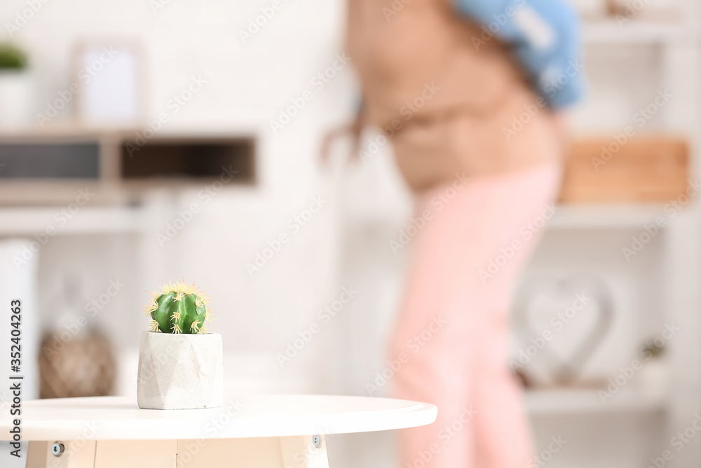 Table with cactus in room. Concept of hemorrhoids Table with cactus in room. Concept of hemorrhoids