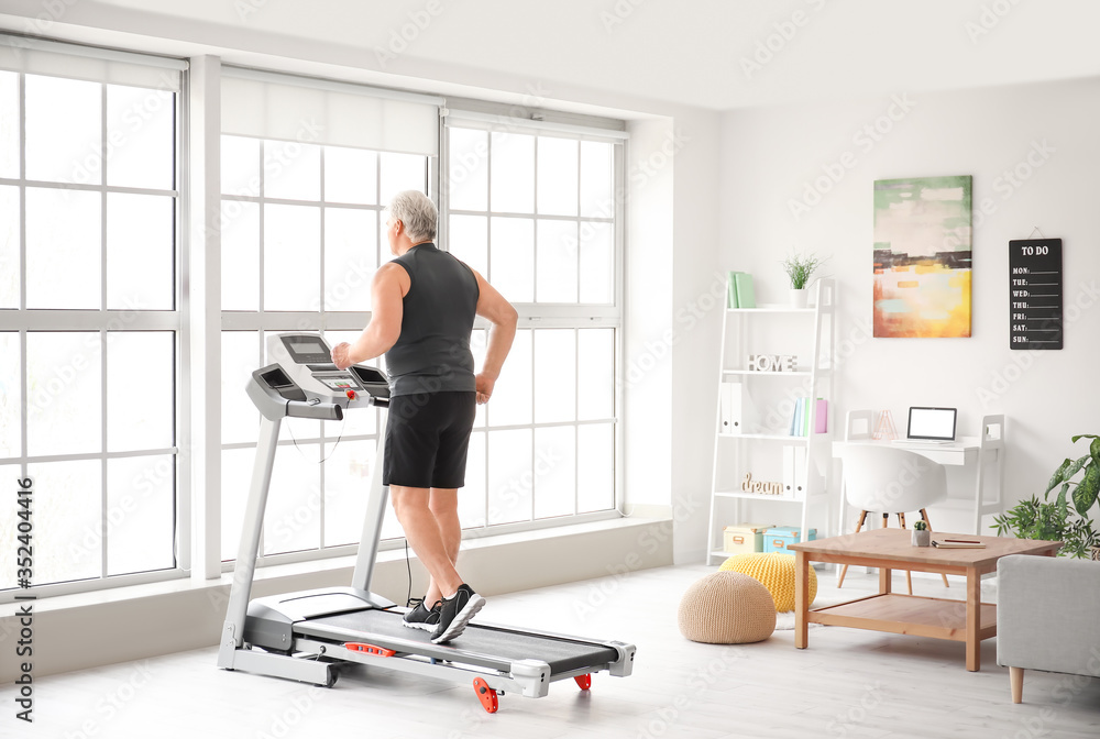 Fototapeta premium Senior man training on treadmill at home