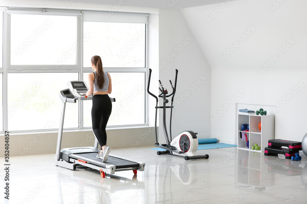 Sporty young woman training on treadmill in gym Sporty young woman training on treadmill in gym