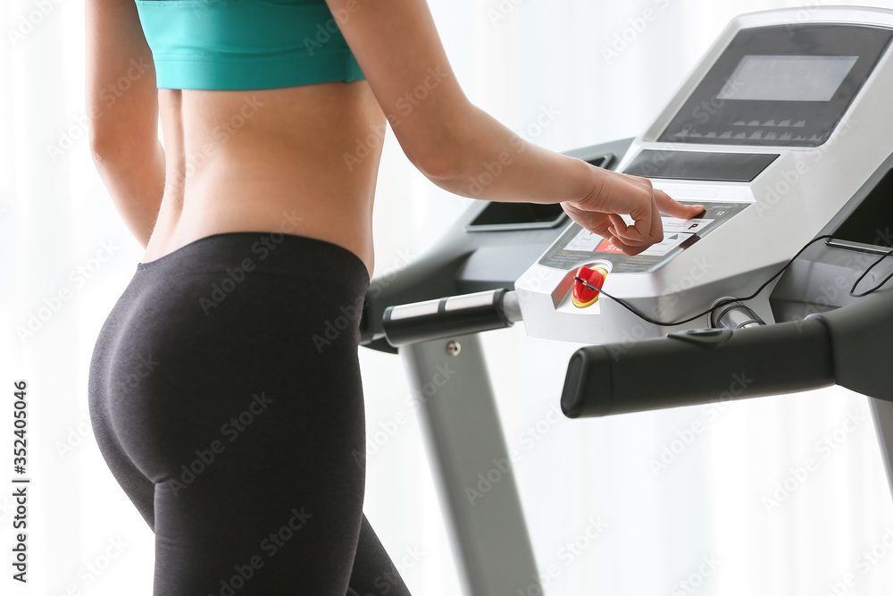 Sporty young woman training on treadmill at home Sporty young woman training on treadmill at home