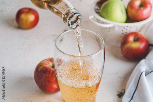 Photo Pouring of apple cider into glass on table
