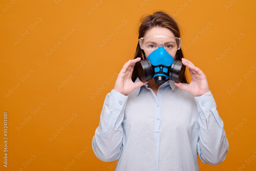 woman in protective equipment in medical mask on yellow background, coronavirus pandemic, look at the camera woman in protective equipment in medical mask on yellow background, coronavirus pandemic, look at the camera