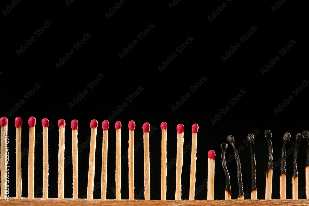 Burnt out and unburnt matches on dark background. Concept of social distance Burnt out and unburnt matches on dark background. Concept of social distance