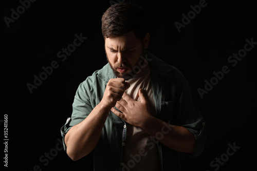 Coughing man on dark background. Concept of epidemic