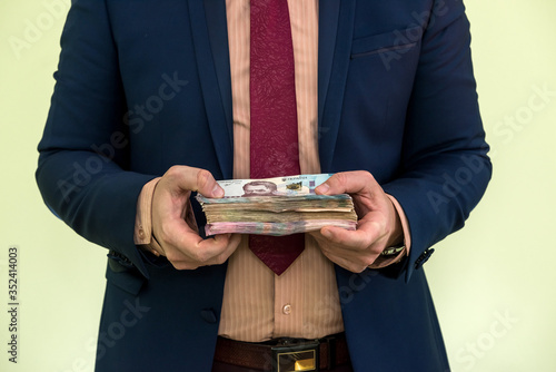 Young businessman holding huge amount of money. New ukraine UAH banknotes 1000 and 500 in the hands of a businessman. Profit